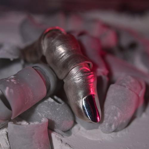 MTHR Full Finger Ring Femine close up on a pile of plastic fingers covered in dust
